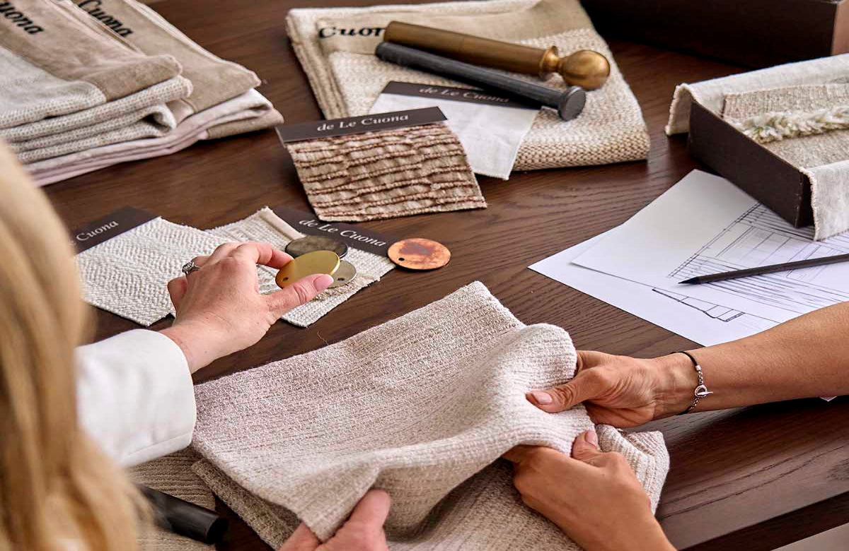 Two people examining fabric swatches on a table with design documents.