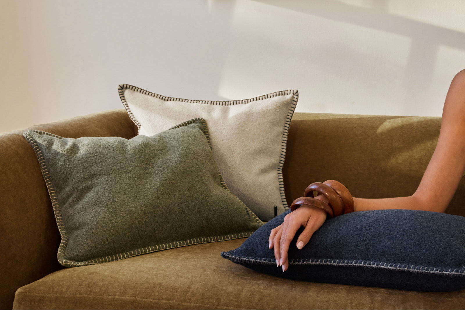 Person sitting on a couch with decorative pillows in a cozy living room setting.