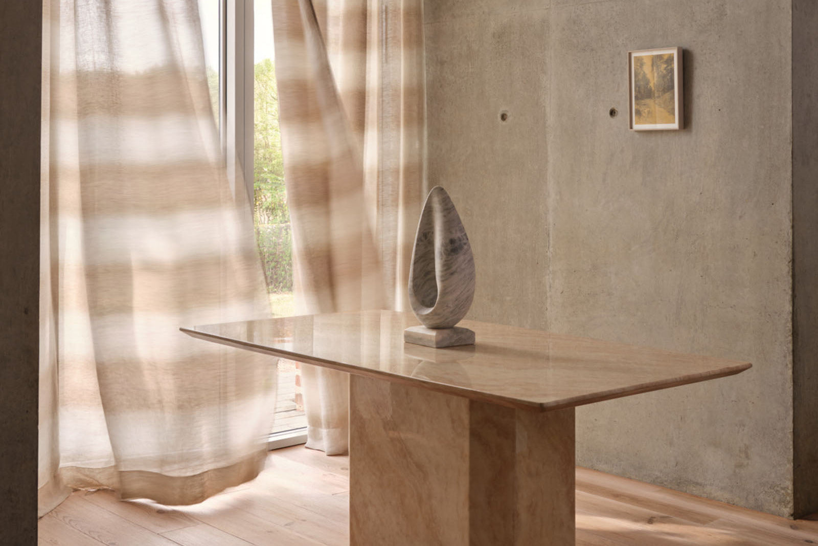 Modern interior with a stone table and sculpture, soft lighting, and neutral tones.
